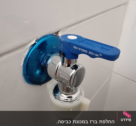 ברז מים עם ידית כחולה על קיר לבן